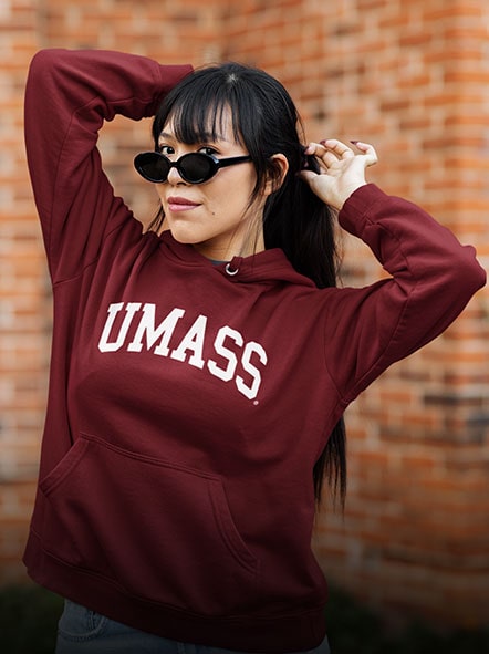 A girl is wearing a University of Massachusetts Amherst Minuteman hoodie of ARCH design