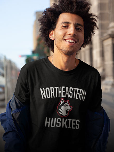 A guy is wearing a northeastern Huskies t-shirt of an Arch design