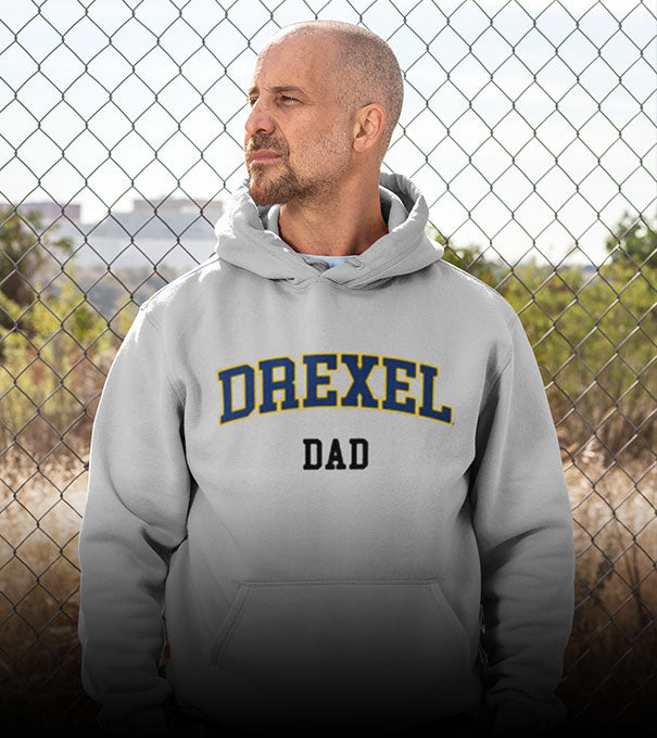 A man is wearing a Drexel University Dragons hoodie with word dad