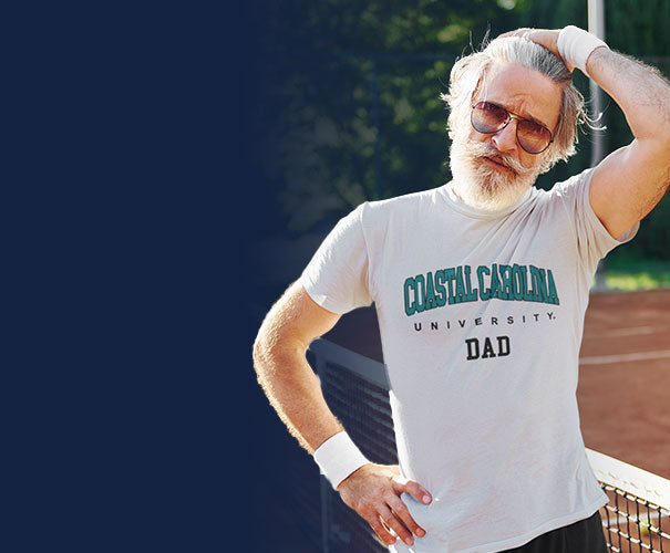 A man is wearing coastal carolina university t-shirt with the word DAD.