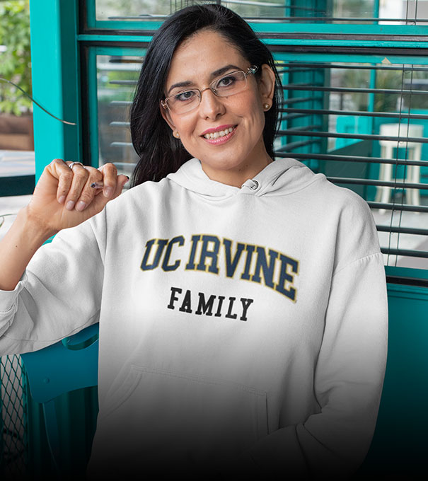 A woman is wearing a University of California UC Irvine Anteaters hoodie with word family